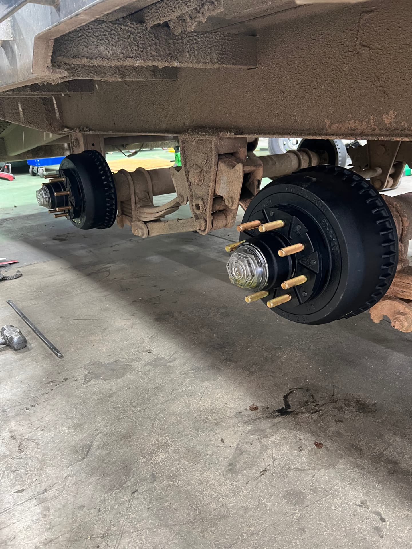 Tandem trailer axles with new black brake drums and hubs installed in the SPARKS shop