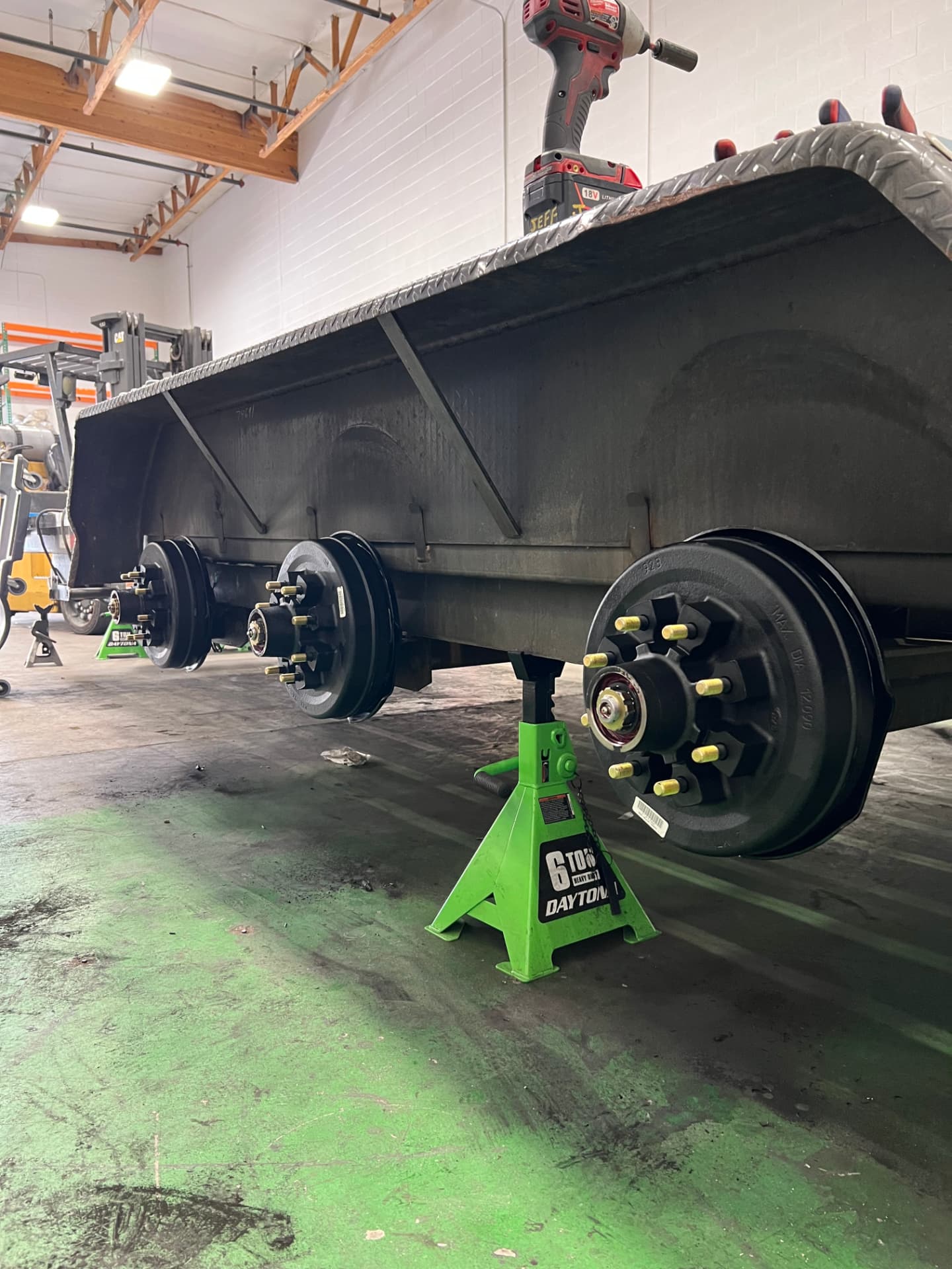Tandem-axle dump trailer on jack stands with new brake drums and hubs installed